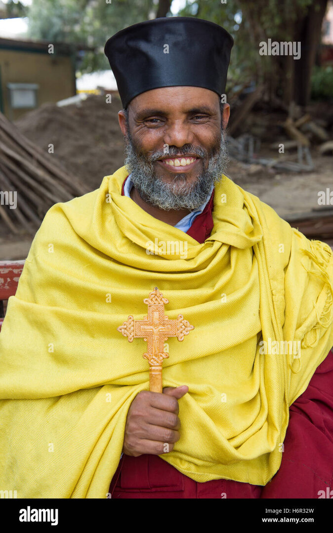 smiling-ethiopian-christian-priest-holding-a-crucifix-in-the-courtyard-H6R32W.jpg